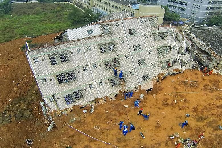 Rescue workers climb up a damaged building on Monday. Some 76 people remain missing under tonnes of earth and wreckage spanning the size of 50 football fields. The landslide on Sunday morning buried 33 buildings in an industrial park in Guangming New