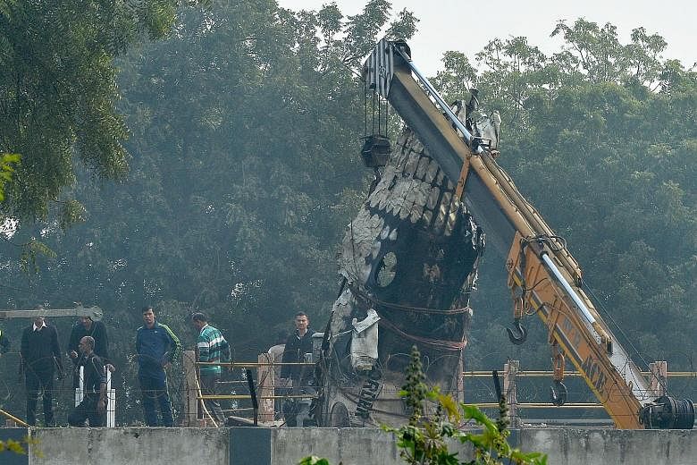 A piece of wreckage being hoisted by a crane after a plane crash yesterday morning near New Delhi's main airport. A chartered Indian aircraft carrying military personnel exploded in a fireball and killed all 10 people on board after crashing into a w