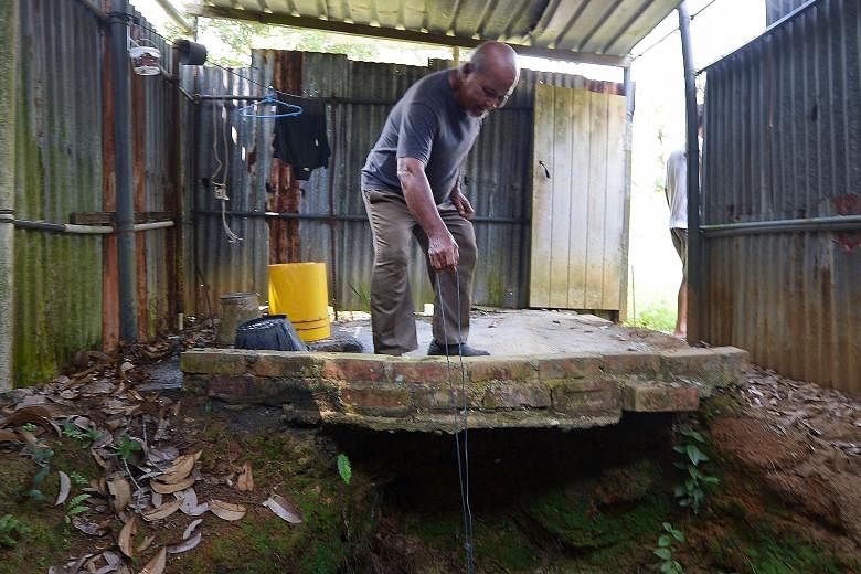 Pulau Ubin resident Ahmad Kassim drawing water from a well opposite his home, which he claims is still safe to drink. Despite warnings from the authorities that water on the island should not be drunk without being boiled first, the 80-year-old was s