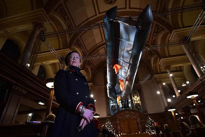 British artist Arabella Dorman in St James's Church, London, with her piece representing a capsized refugee boat. Migrant groups have expressed worry over anti-refugee policies.