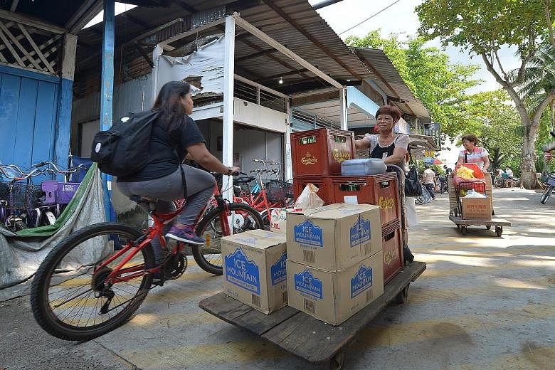 Ms Goh Lai Guat (far right), 60, and her sister pushing trolleys of supplies and bottled water to their food stall on Pulau Ubin after an advisory from the authorities on the usage of well water. Top, visitors looking at a well which is covered to pr