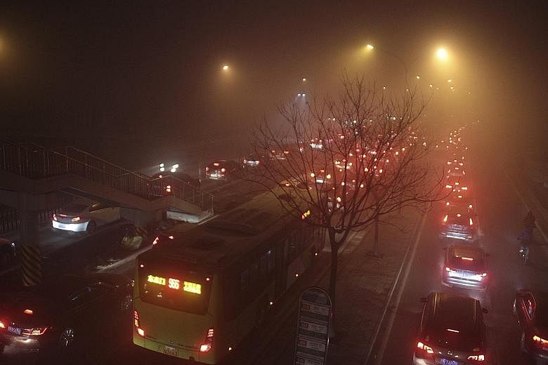 Vehicles are seen stuck in traffic amid heavy smog in Beijing, China, early yesterday. Beijing's cancellation of the red alert meant traffic restrictions were lifted and schools reopened despite the lingering smog.