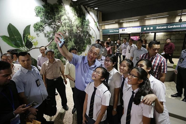 Prime Minister Lee Hsien Loong taking a wefie with students from Methodist Girls' School yesterday during the Downtown Line 2's opening ceremony at Botanic Gardens Station.