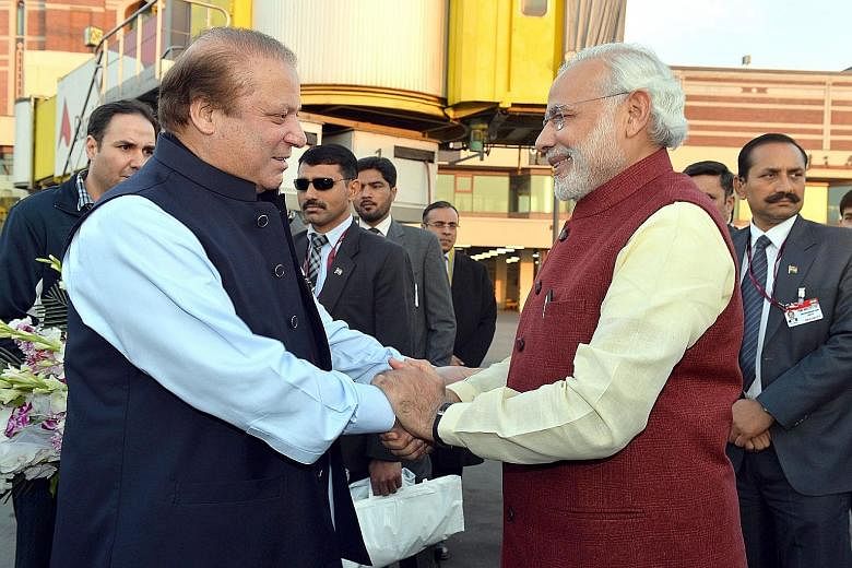 Indian Prime Minister Narendra Modi (above, right) is welcomed by the Prime Minister of Pakistan, Mr Nawaz Sharif, at the airport in Lahore, Pakistan, on Friday. The visit was initiated over a phone call Mr Modi made to greet Mr Sharif on his 66th bi