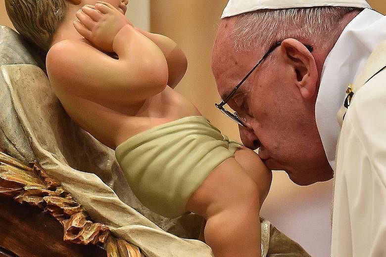 Pope Francis kissing a figurine of baby Jesus on Christmas Eve at St Peter's Basilica. Security was tight at the Vatican.