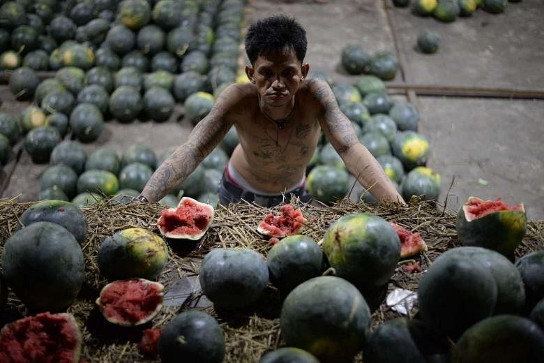 A worker looks at damaged watermelon at a market in Manila on December 27.