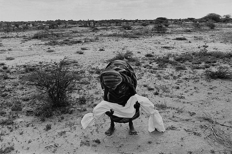 Lifting a dead son to carry him to a mass grave during the famine in Somalia (1992) by James Nachtwey.
