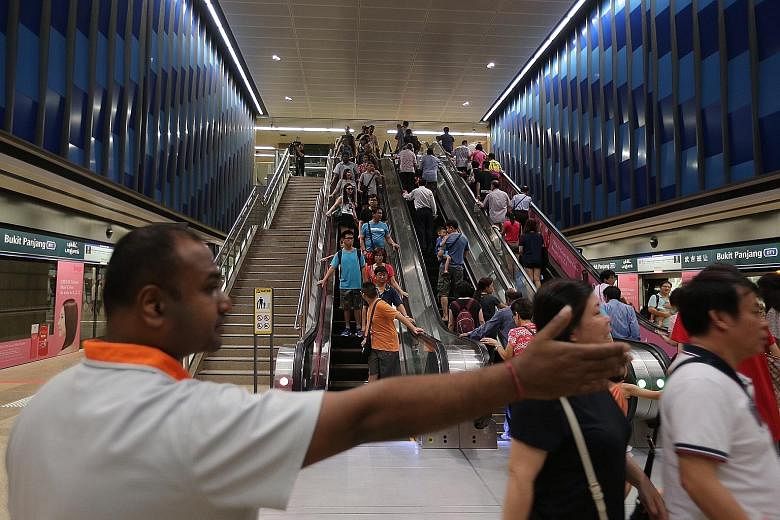 A staff member directing the crowd at Bukit Panjang station. Rides starting and ending on the Downtown Line will be free till Jan 1.