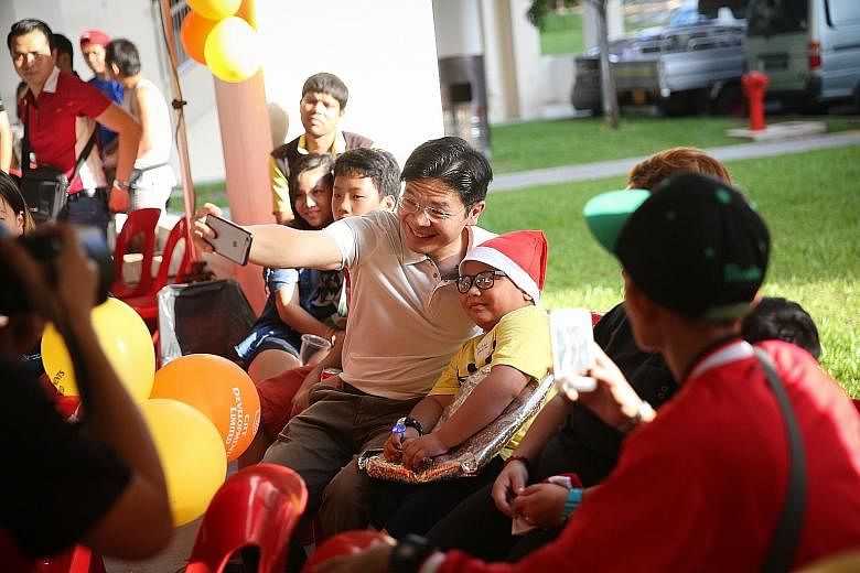 Minister for National Development Lawrence Wong taking a selfie with schoolboy Mohamad Rafael Effendy Razali yesterday after presenting him with a festive gift from his wishlist. The seven-year-old had asked for a backpack after his previous one brok