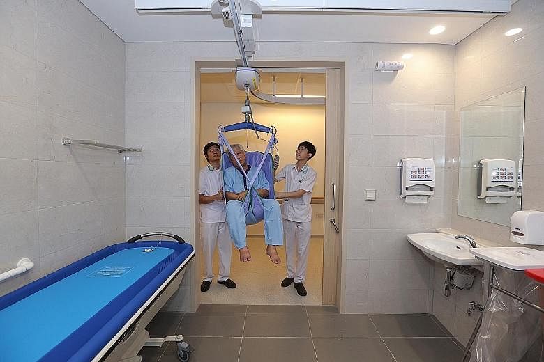 A patient being moved from bed to toilet with the help of a hoist (above). With these hoists, two nurses are able to move a heavy, non-ambulatory patient from bed to chair or bathroom. The newly opened Yishun Community Hospital (below) has four of th