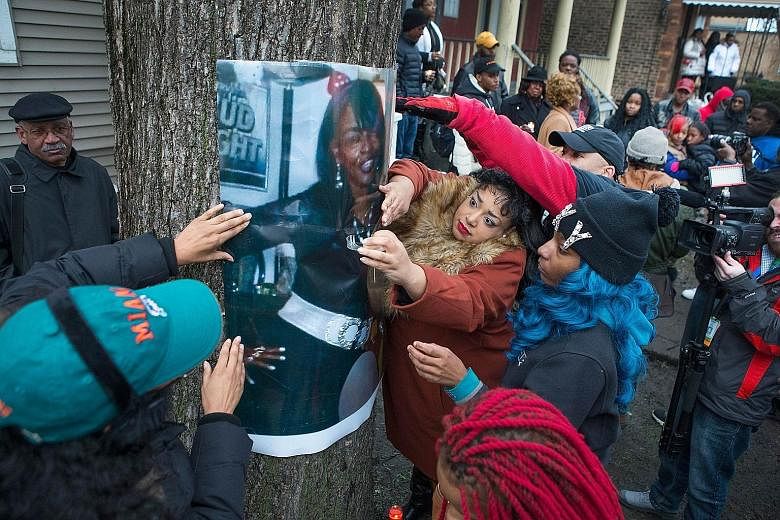 The daughters of Ms Bettie Jones, along with friends and supporters, displaying a picture of her during a vigil outside the family home in Chicago on Sunday.