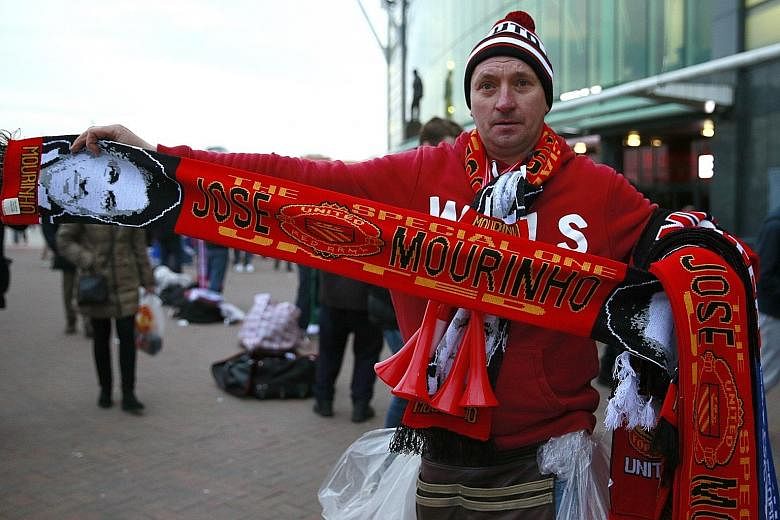 A street seller with a Manchester United scarf that has Jose Mourinho's face woven onto it. The scarves were being sold outside Old Trafford prior to the United-Chelsea clash.