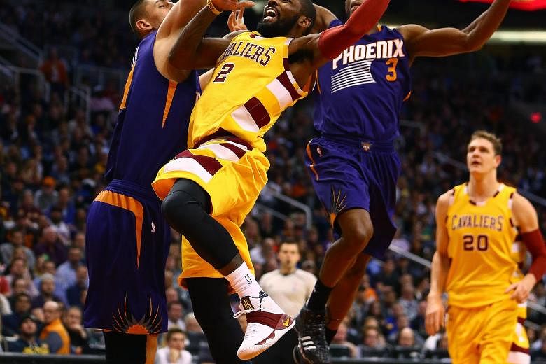 Cleveland Cavaliers guard Kyrie Irving (centre) driving to the basket against Phoenix Suns guard Brandon Knight (right) and centre Alex Len. The Cavs won 101-97 to avoid their season's first three-game losing streak.