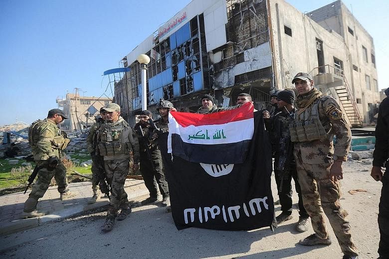 Members of Iraq's security forces (right) holding an Iraqi flag with an ISIS flag, which they had pulled down at a Ramadi government complex, while counterterrorism forces (below, right) celebrate on Monday after the city was retaken from ISIS. The a