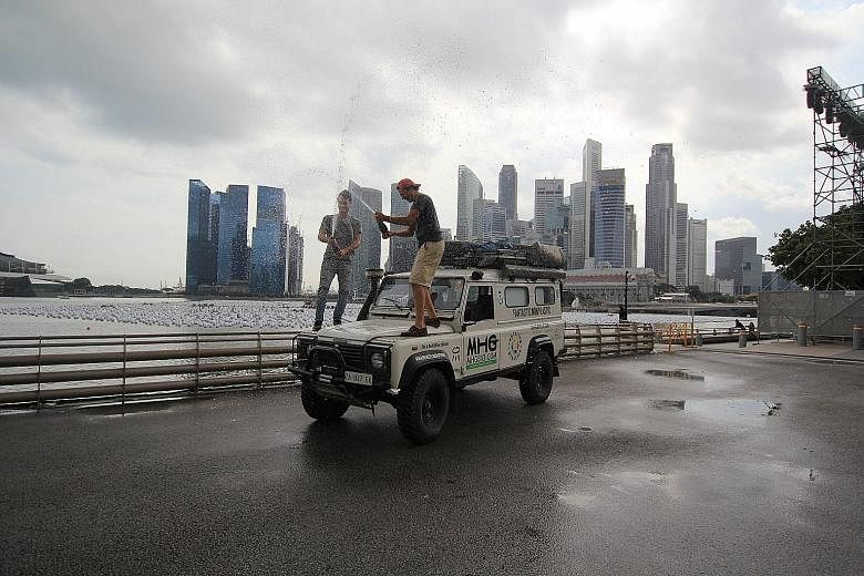 Above: Mr Sabatini (left) and Mr Poccianti celebrate their arrival here by popping champagne atop their Land Rover with the Singapore skyline in the background. Above, left: On part of their road trip, Mr Poccianti (left) and Mr Sabatini had to be ac