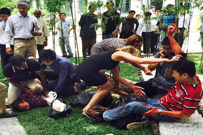 Two passers-by (far left) helped to pin down Arun while others attended to Mr Kang Tie Tie (left), who was bleeding profusely after being stabbed in the robbery in Raffles Place on Nov 14, 2014. Arun was yesterday sentenced to 12 years' jail and 24 s