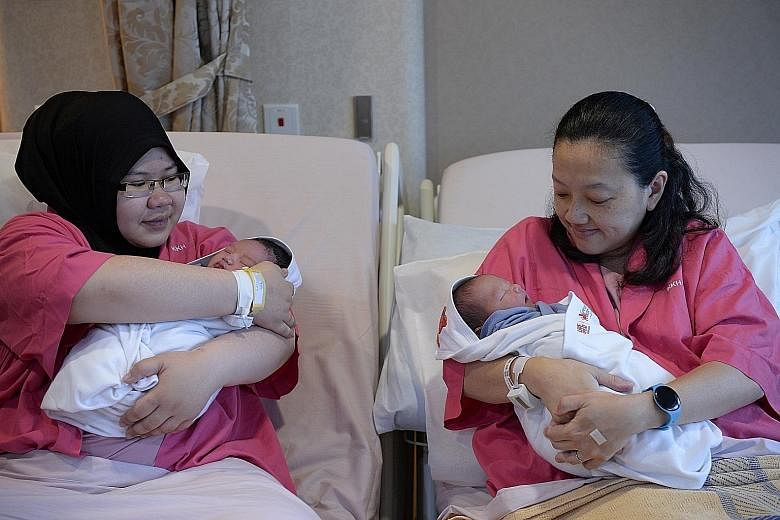 Happy mums Ms Khairunnisa (left) and Ms Tee cradling their newborn sons at KKH yesterday.