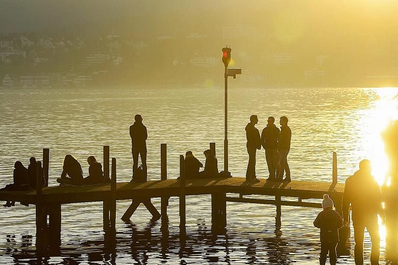 (Left) People taking advantage of the unseasonably warm, springlike winter in Europe to take a stroll at Lake Zurich, in Switzerland. (Above) A flowering tree, an uncommon sight in December, at the Rignon Park in Turin, Italy.
