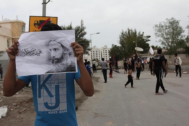 An activist carrying a poster of prominent cleric Nimr al-Nimr during a demonstration yesterday against his execution in Manama, Bahrain.