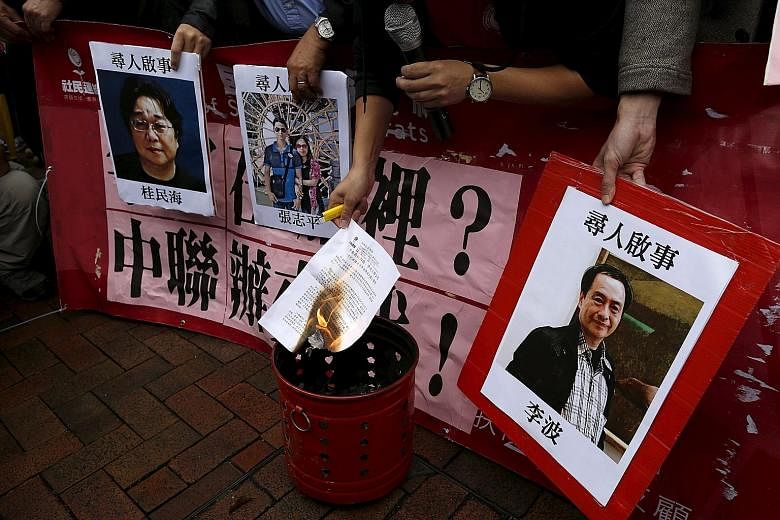 A demonstrator burning a letter next to pictures of missing people linked to a Hong Kong bookstore during a protest outside China's representative office yesterday. The photo on the right is of bookseller Lee Bo.