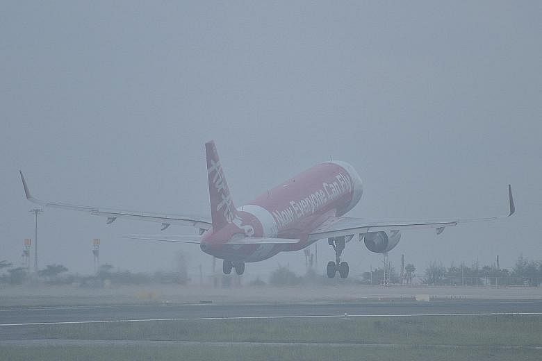 A plane taking off at the haze-hit Phuket International Airport in October. Some travellers who faced flight disruptions due to the haze have found they cannot make claims under their travel insurance policies. A man on an electric scooter wearing a 