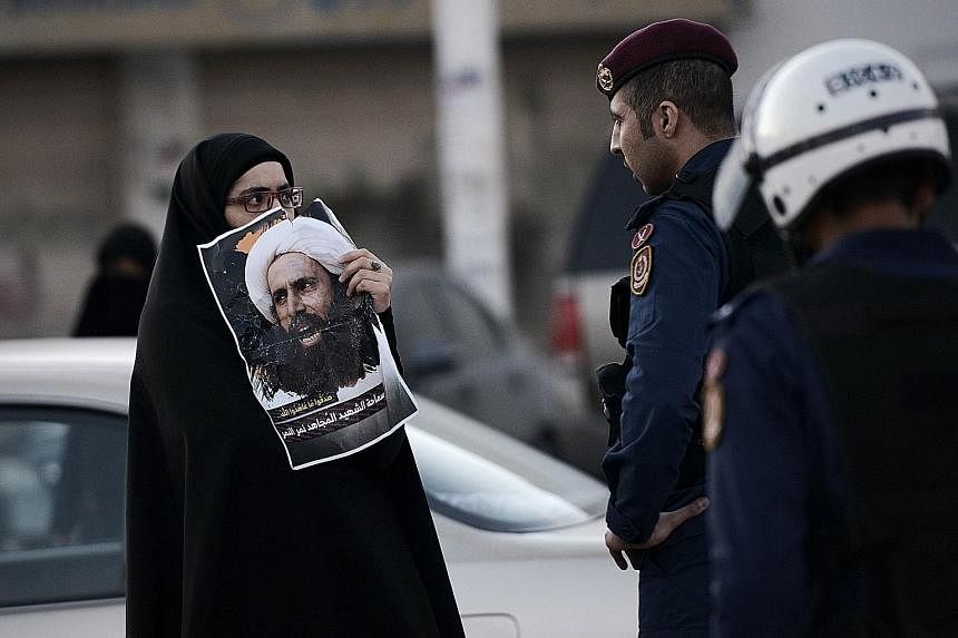(Left) Iraqi protesters burning an effigy of a member of the Saudi ruling family during a demonstration in Baghdad on Monday against Saudi Arabia's execution of Shi'ite cleric Nimr al-Nimr. (Above) In Bahrain, a woman holding a poster of Nimr during 
