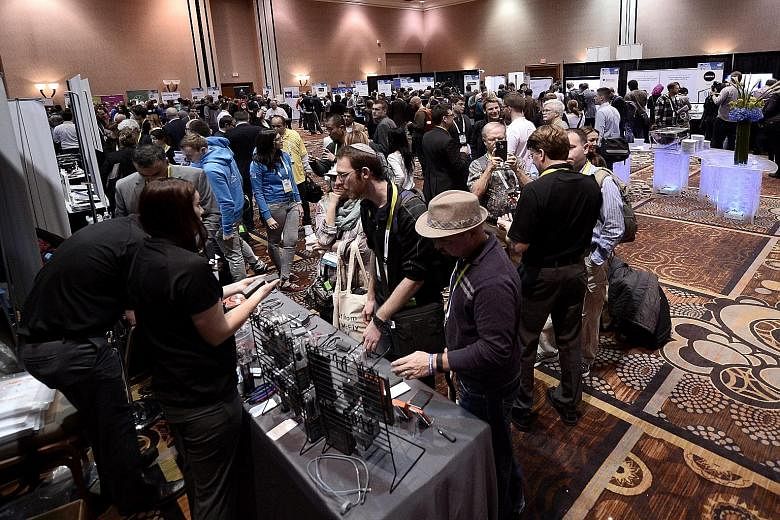 Left: Members of the media trying new products at a Consumer Electronics Show event at the Mandalay Bay Resort and Casino in Las Vegas on Monday. Above: A Samsung executive using the Samsung Gear S2 smartwatch to control a new Samsung TV. Other featu