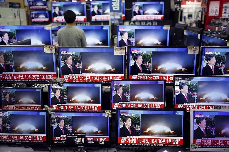 A sales assistant in Seoul, South Korea, watching a news broadcast on North Korea's supposed hydrogen bomb test yesterday. A picture taken from North Korean TV showing a message from Mr Kim on starting the year with the "thrilling sound of the first 