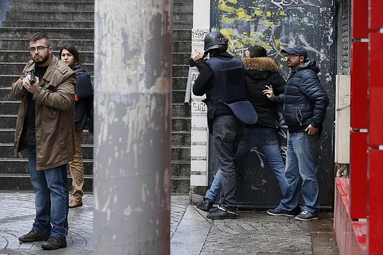 French police checking a pedestrian as they secure the area after a knife-wielding man was shot dead at a police station in the 18th district in Paris yesterday. The man was shouting "Allahu Akbar", which means "God is the greatest" in Arabic, as he 