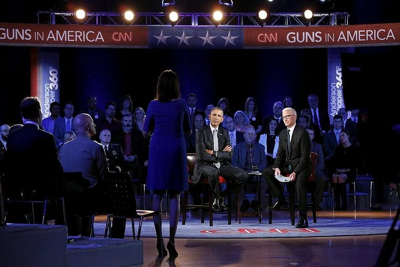 President Barack Obama (centre) listening to Mrs Taya Kyle, widow of Navy Seal Chris Kyle, during the town hall forum on gun control at George Mason University in Fairfax, Virginia. The event was hosted by CNN's Anderson Cooper (right).