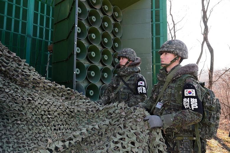 South Korean soldiers removing the camouflage as the loudspeakers were put to work again at the border yesterday. Seoul broadcast K-pop songs such as Bang, Bang, Bang by the group Big Bang and propaganda messages aimed at the North in retaliation aga
