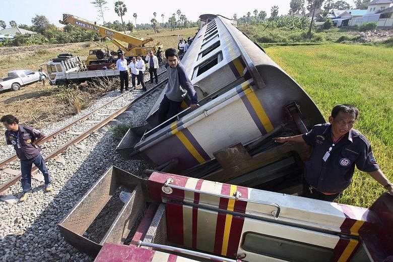Thai railway workers and rescuers recovering the wreckage of a derailed passenger train in Phetchaburi province, Thailand, yesterday. Three people were killed and over 30 injured when the passenger train collided with a cattle truck at a railway cros