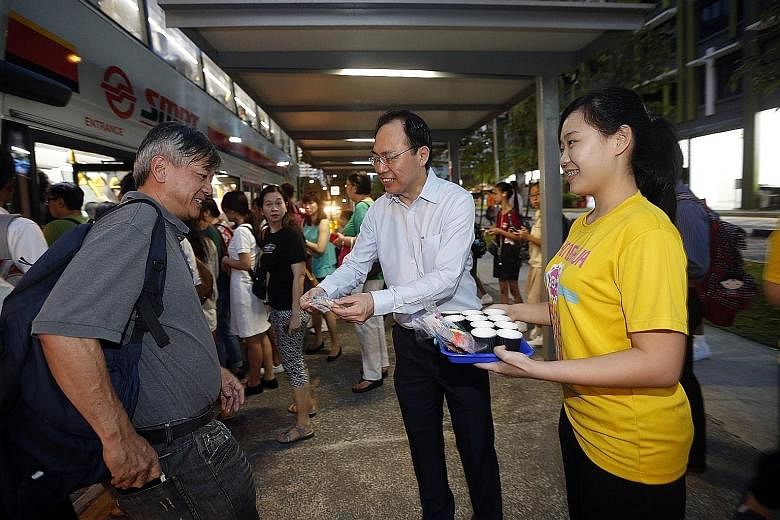 Holland-Bukit Timah GRC MP and Zhenghua grassroots adviser Liang Eng Hwa (centre), as well as grassroots leaders from the Zhenghua division, giving out cookies and around 300 cups of coffee and Milo on Thursday to perk up morning commuters in the fir