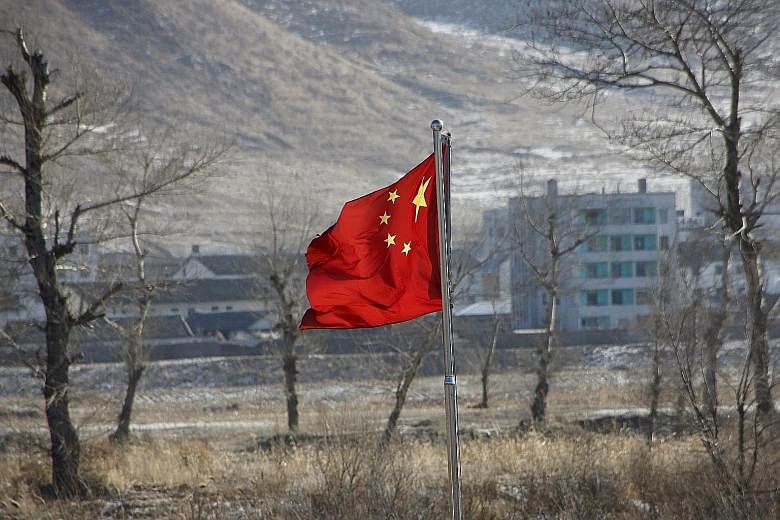 China's national flag flutters on the Chinese side of the banks of the Tumen River, with a North Korean village seen behind. The two countries share a 1,300km border in China's strategic north-eastern region.