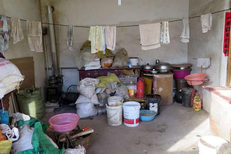 Madam Zhang in the cluttered bedroom of her squalid home, which also has a sparsely furnished living area (below, left), in the remote Aihetan village in Hebei province. Madam Zhang is gradually going blind as her family is too poor to take her to