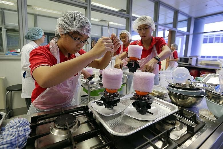Xinmin Secondary School student Ang Yi Pin (far left), 14, places a piece of cotton candy on her team's ice-cream creation made from sweet potatoes and passion fruit. The creation - called the Metamorphic - was inspired by DC Comics superhero Metamor