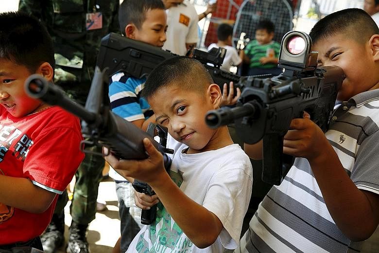 Children playing with weapons at a military facility in Bangkok during Thailand's National Children's Day celebrations yesterday. Army barracks opened their doors to youngsters, with displays of weapons and vehicles as part of the celebrations. Thail