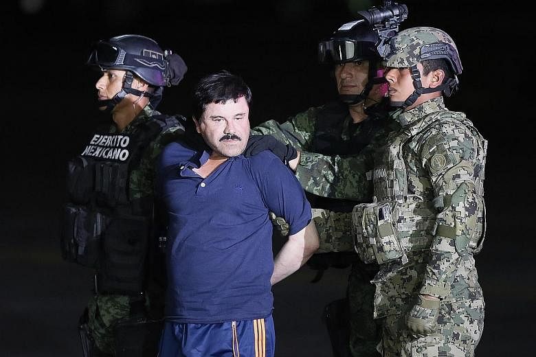 Mexican drug lord Joaquin Guzman Loera being escorted to a helicopteron Friday to be transferred to the prison in Mexico he escaped from last year.
