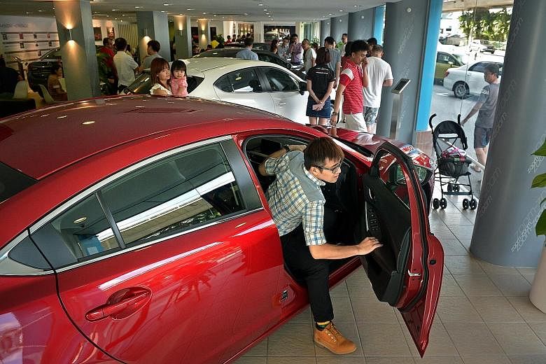 Potential buyers at the Mazda showroom yesterday. Mazda senior marketing manager David Chung said visitor numbers increased by 30 to 40 per cent after the latest round of COE bidding saw premiums fall. Dealers said prices of cars up to 1,600cc and 13