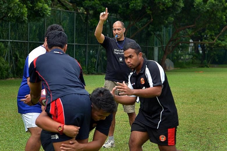 Inoke Afeaki (with hand raised), technical director and head coach of the national rugby team, giving instructions during a training session in 2013.