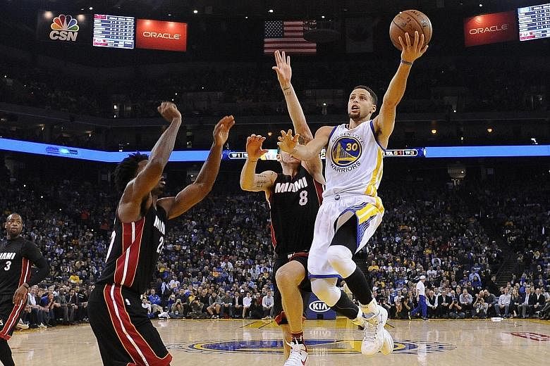 Golden State Warriors guard Stephen Curry (right) shooting against two Miami players. The Warriors cruised to a 111-103 victory over the Heat with Curry recording his 16th 30-point game of the season.