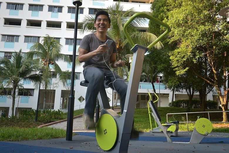 Playpoint managing director Jason Sim demonstrating how to use the outdoor exercise equipment to convert exercise energy into electricity to charge his mobile phone at the Bukit Panjang Ring Road fitness corner.