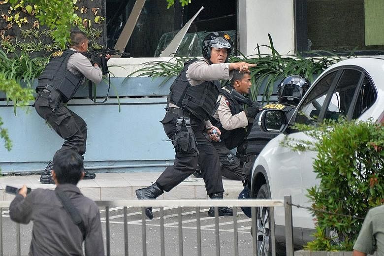 Indonesian police gathering outside a restaurant near the scene of the attack (above) and taking position (below) with their weapons as they pursued suspects outside a cafe yesterday. (Left) An injured foreigner lying on the ground outside the popula