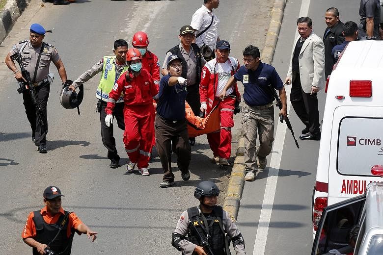 Indonesian police gathering outside a restaurant near the scene of the attack (above) and taking position (below) with their weapons as they pursued suspects outside a cafe yesterday. (Left) An injured foreigner lying on the ground outside the popula