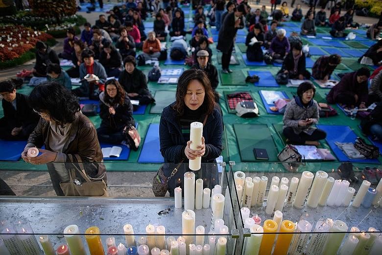 A parent prays for students sitting the annual college entrance exams at the Jogye Buddhist temple in Seoul last November. Koreans believe that high exam scores will decide their fates and future. Hence, there is tremendous pressure on students to sc