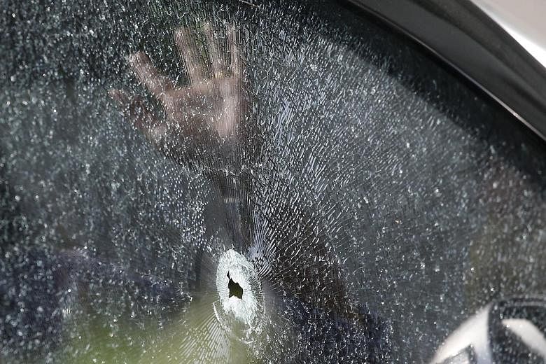 An Indonesian policeman yesterday inspecting a bullet hole in the window of a car in front of the Starbucks cafe in Jakarta that was attacked by militants.