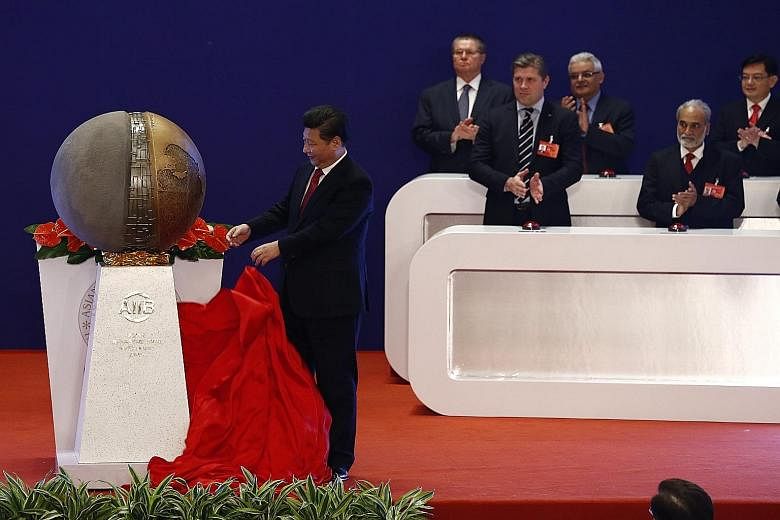 China's President Xi Jinping (far left) unveiling a sculpture in the presence of other delegates - including Singapore's Finance Minister Heng Swee Keat (back row, far right) - during yesterday's opening ceremony of the Asian Infrastructure Investmen
