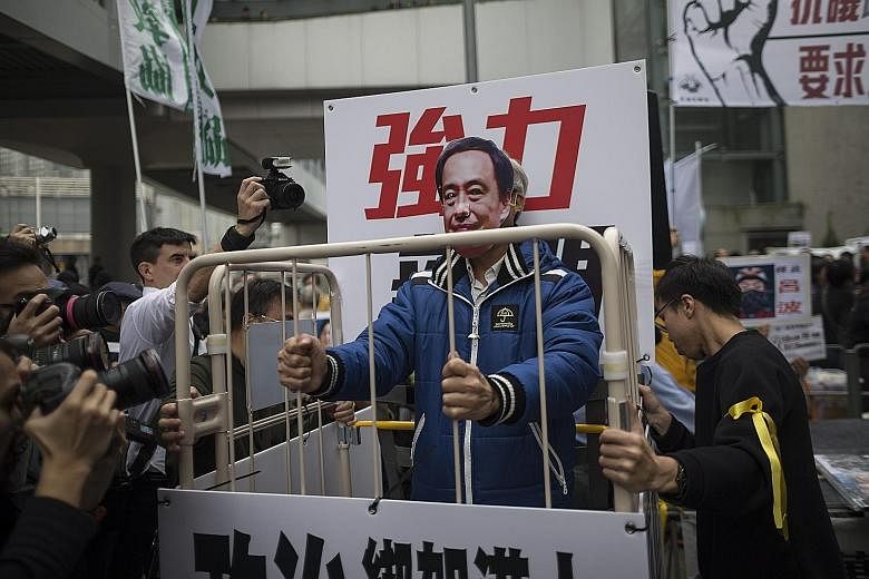 A protester wearing a mask of missing bookshop co-owner Lee Bo stands behind bars during a protest in Hong Kong last Sunday. Booksellers have recently landed in hot water for peddling books that claim to give an insider's view of the public and priva