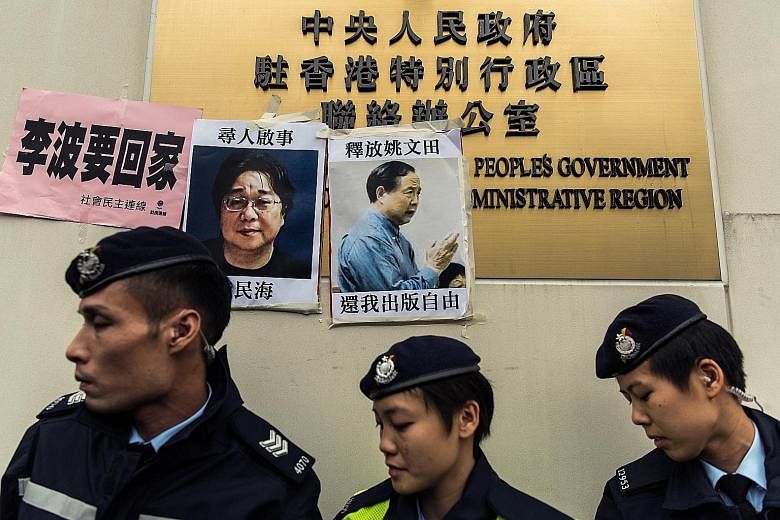Hong Kong police in front of missing-person notices for Mr Gui Minhai (left), one of five missing booksellers linked to the Mighty Current publishing house, and Hong Kong publisher Yao Wentian (right), who had been planning to release a book critical