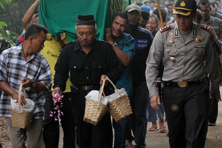 An armed police officer accompanying mourners during the funeral procession of terror attack victim Rico Hermawan at a cemetery in Boyolali, Indonesia's central Java island, yesterday. The death toll from last Thursday's attack has risen to eight, af